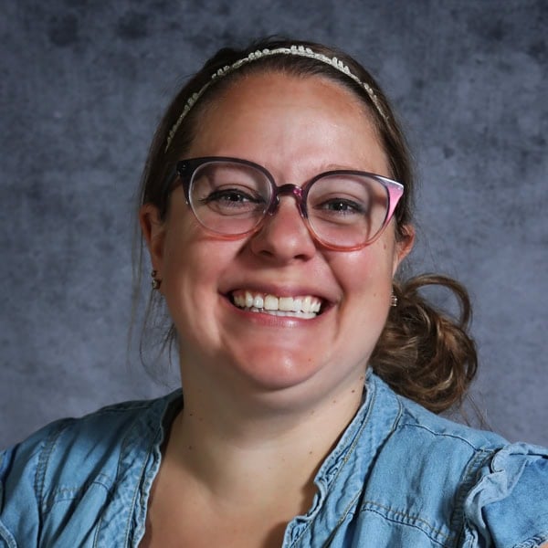 Person smiling wearing glasses and headband.