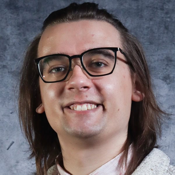 Person with glasses smiling, gray background