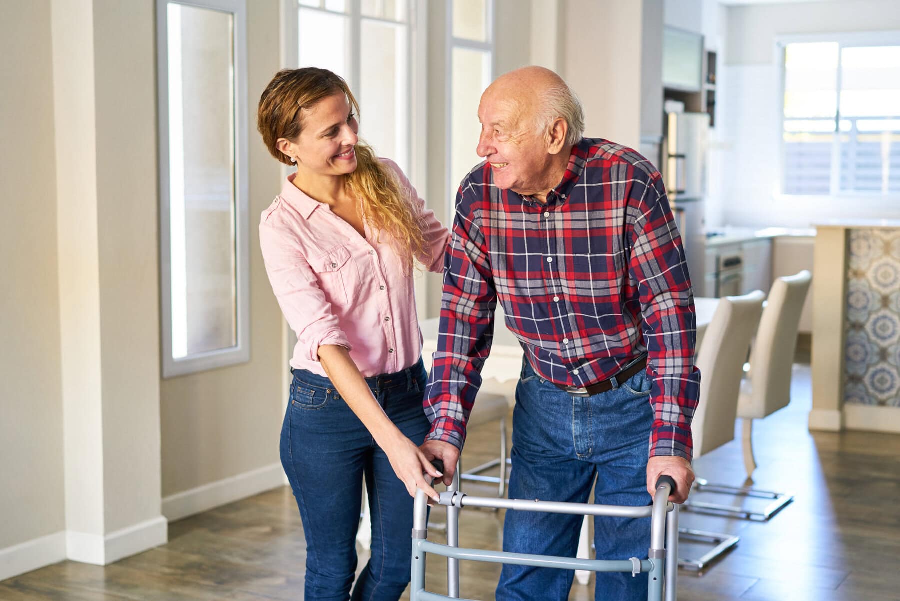 Caregiver assisting elderly man with walker.
